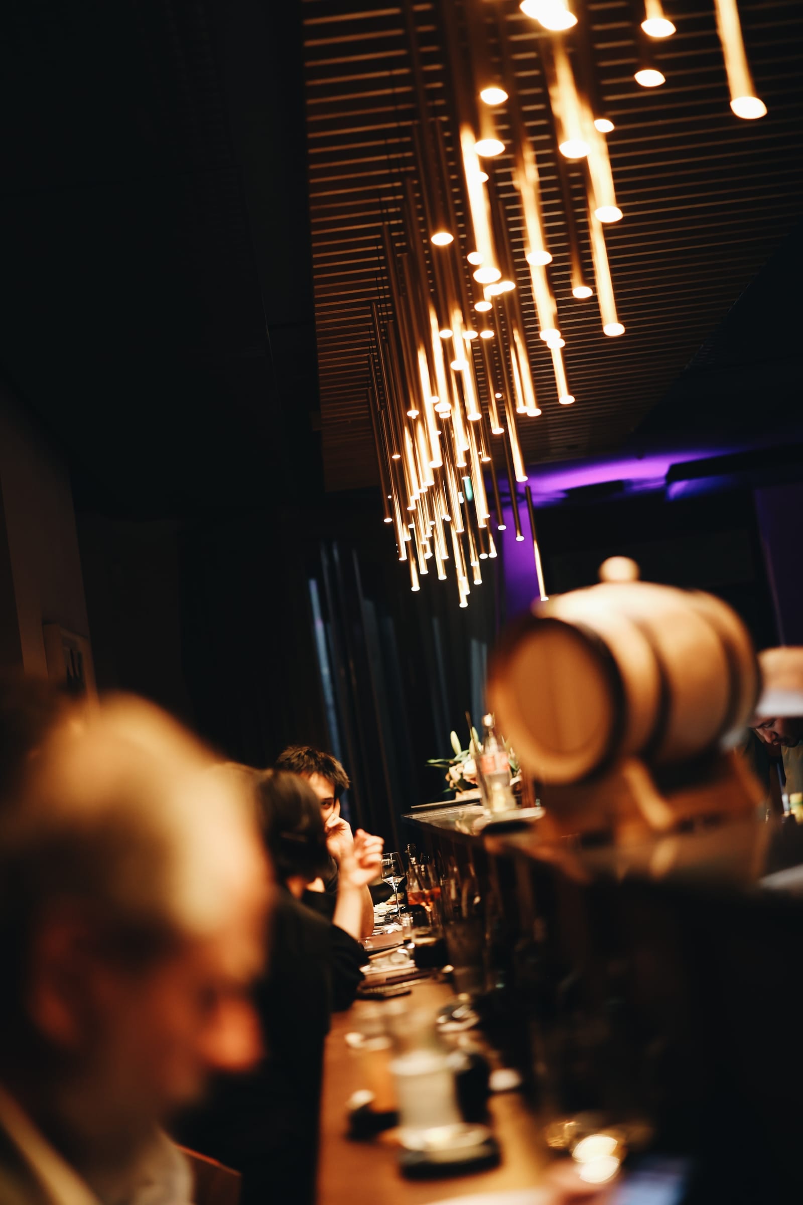 Gäste an der Bar unter den Lichtstäben
