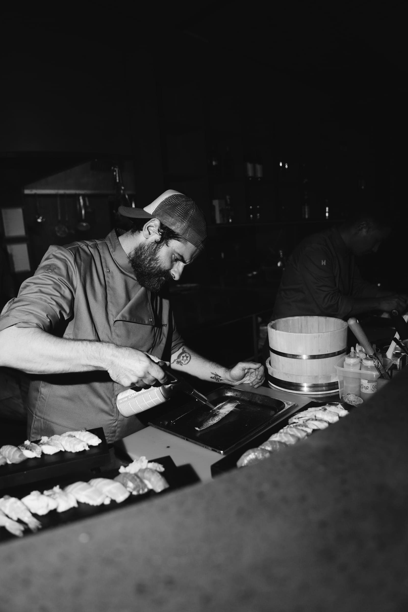 Sushi-Koch schneidet Fisch an der offenen Bar